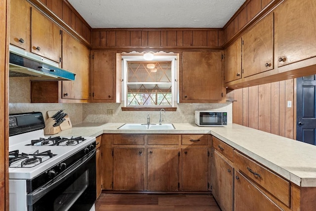 814 W Bell Ave, Rockdale, TX 76567 - kitchen with white gas range oven, under cabinet range hood, black microwave, a sink, and light countertops