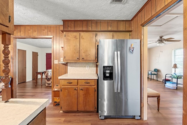 814 W Bell Ave, Rockdale, TX 76567 - kitchen with stainless steel refrigerator with ice dispenser, wooden walls, light countertops, a ceiling fan, and a textured ceiling