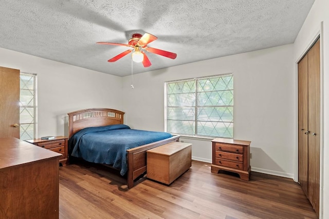 814 W Bell Ave, Rockdale, TX 76567 - bedroom featuring wood finished floors, multiple windows, a closet, a textured ceiling, and ceiling fan