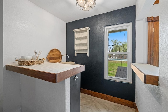 13201 Stillforest St, Austin, TX 78729 - kitchen with baseboards, tile countertops, and a textured wall