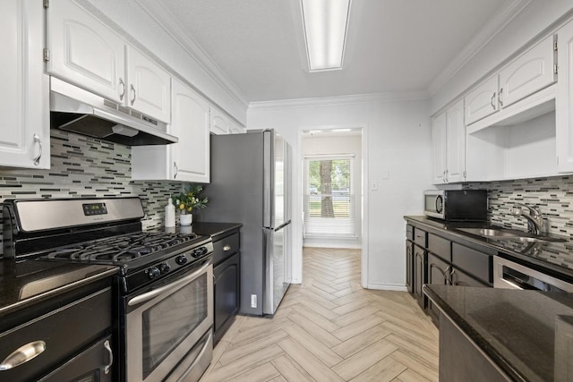 13201 Stillforest St, Austin, TX 78729 - kitchen with stainless steel appliances, under cabinet range hood, dark countertops, white cabinetry, and ornamental molding