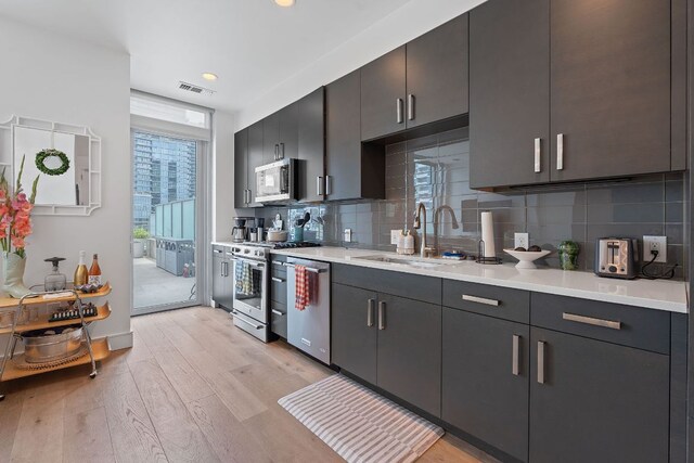 222 W Ave Unit 1001, Austin, TX 78701 - kitchen with appliances with stainless steel finishes, a sink, light wood-style floors, light countertops, and recessed lighting
