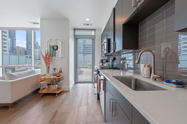 222 W Ave Unit 1001, Austin, TX 78701 - kitchen with a sink, light wood finished floors, appliances with stainless steel finishes, plenty of natural light, and recessed lighting