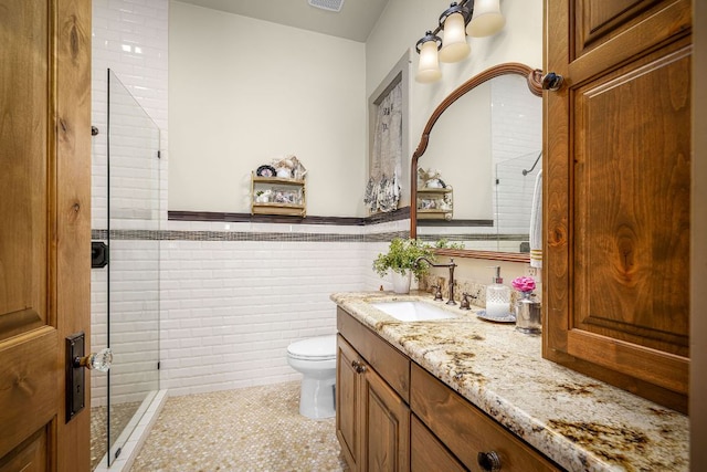 1606 Bordeaux Blanc, New Braunfels, TX 78132 - bathroom featuring vanity, tiled shower, toilet, a wainscoted wall, and tile walls