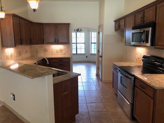 22340 Briarcliff Dr, Spicewood, TX 78669 - kitchen featuring stainless steel appliances, a sink, light tile patterned floors, a peninsula, and tasteful backsplash