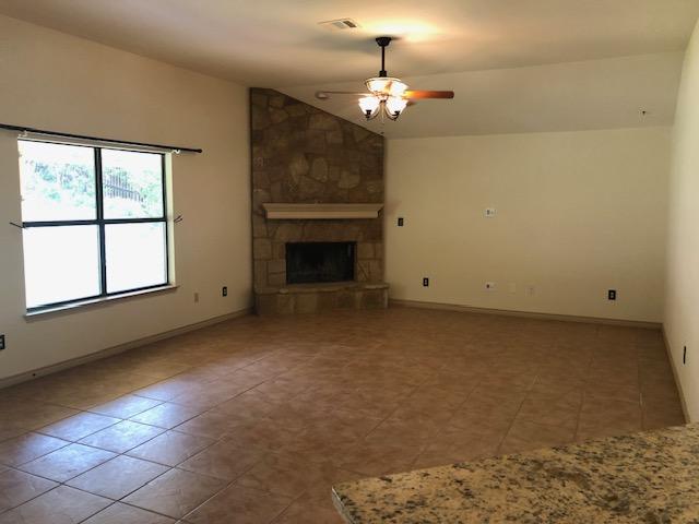 22340 Briarcliff Dr, Spicewood, TX 78669 - unfurnished living room featuring ceiling fan, tile patterned floors, lofted ceiling, a fireplace, and baseboards