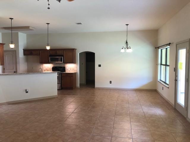 22340 Briarcliff Dr, Spicewood, TX 78669 - kitchen featuring stainless steel microwave, stove, arched walkways, light countertops, and pendant lighting