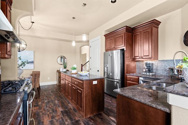 121 White Wash, Dripping Springs, TX 78620 - kitchen with stainless steel appliances, wall chimney range hood, a sink, arched walkways, and dark stone countertops