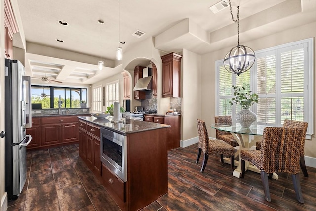 121 White Wash, Dripping Springs, TX 78620 - kitchen featuring appliances with stainless steel finishes, dark wood-style flooring, wall chimney exhaust hood, a kitchen island, and a chandelier