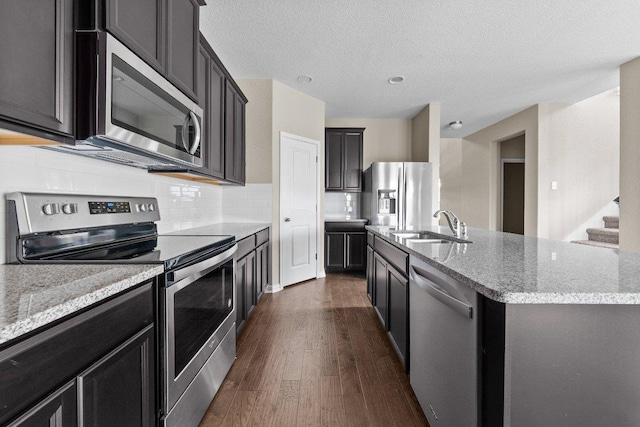 202 Westfield St, Hutto, TX 78634 - kitchen featuring appliances with stainless steel finishes, light stone countertops, dark wood finished floors, backsplash, and a textured ceiling