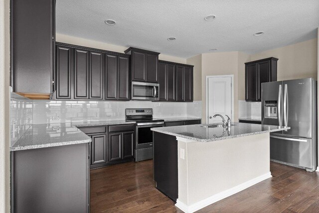 202 Westfield St, Hutto, TX 78634 - kitchen with stainless steel appliances, a sink, dark wood-style floors, a kitchen island with sink, and backsplash