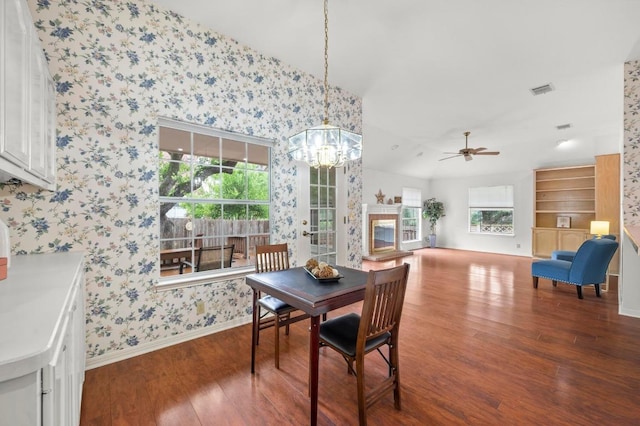 10601 Beckwood Dr, Austin, TX 78726 - dining space with wallpapered walls, wood finished floors, a chandelier, a ceiling fan, and a glass covered fireplace