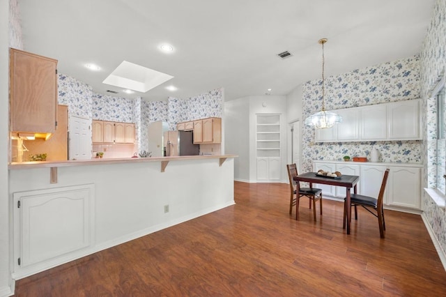 10601 Beckwood Dr, Austin, TX 78726 - kitchen with stainless steel fridge with ice dispenser, a skylight, a chandelier, wallpapered walls, and a peninsula