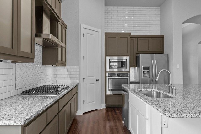 20525 Martin Ln, Pflugerville, TX 78660 - kitchen with stainless steel appliances, wall chimney exhaust hood, a sink, arched walkways, and dark wood-style floors