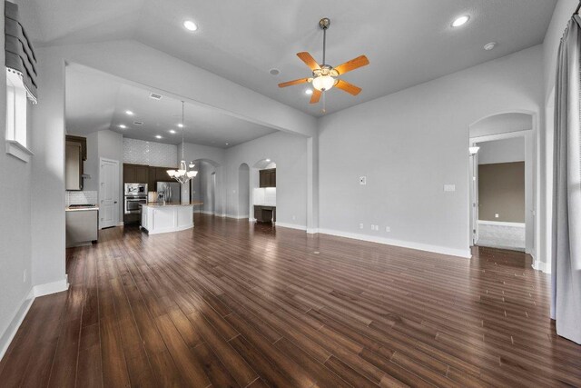 20525 Martin Ln, Pflugerville, TX 78660 - unfurnished living room with arched walkways, a ceiling fan, dark wood-type flooring, vaulted ceiling, and a chandelier