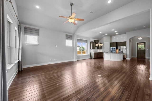 20525 Martin Ln, Pflugerville, TX 78660 - unfurnished living room featuring a ceiling fan, vaulted ceiling, healthy amount of natural light, arched walkways, and dark wood-type flooring