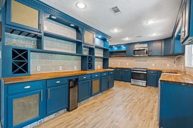 1515 Mearns Meadow Blvd, Austin, TX 78758 - kitchen with wood counters, stainless steel appliances, a sink, open shelves, and a textured ceiling