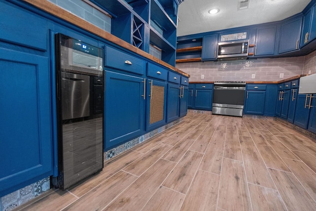 1515 Mearns Meadow Blvd, Austin, TX 78758 - kitchen with stainless steel appliances, blue cabinetry, light wood-type flooring, tasteful backsplash, and a textured ceiling