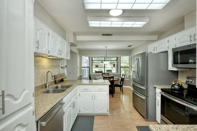 1604 W Creek Loop, Round Rock, TX 78681 - kitchen with stainless steel appliances, a peninsula, white cabinets, and light wood-type flooring