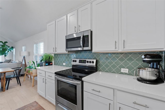 200 Ottaviano Way, Hutto, TX 78634 - kitchen featuring appliances with stainless steel finishes, light countertops, decorative backsplash, white cabinets, and lofted ceiling