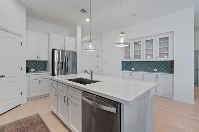 200 Ottaviano Way, Hutto, TX 78634 - kitchen with appliances with stainless steel finishes, light wood-style floors, tasteful backsplash, white cabinets, and a kitchen island with sink