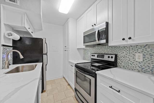 3204 Menchaca Rd Unit 405, Austin, TX 78704 - kitchen featuring appliances with stainless steel finishes, decorative backsplash, white cabinets, light stone countertops, and a textured ceiling