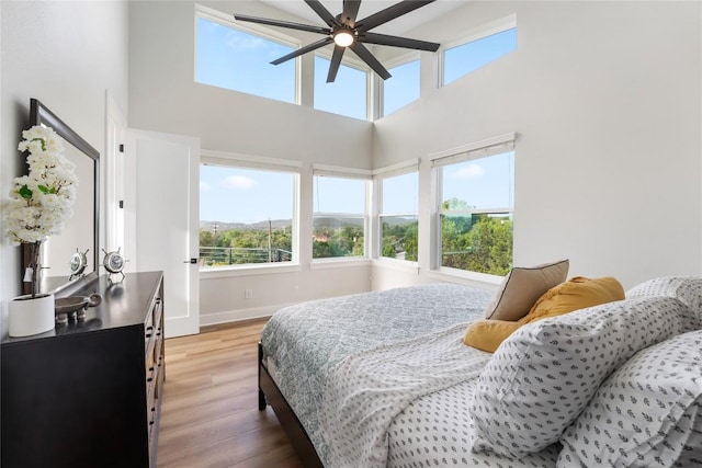 11204 Oak St, Jonestown, TX 78645 - bedroom with light wood finished floors, multiple windows, a high ceiling, baseboards, and ceiling fan