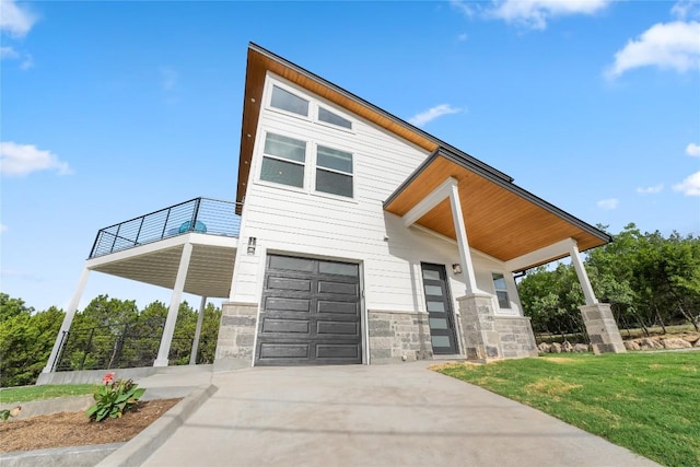11204 Oak St, Jonestown, TX 78645 - contemporary home with an attached garage, stone siding, driveway, a balcony, and a front lawn