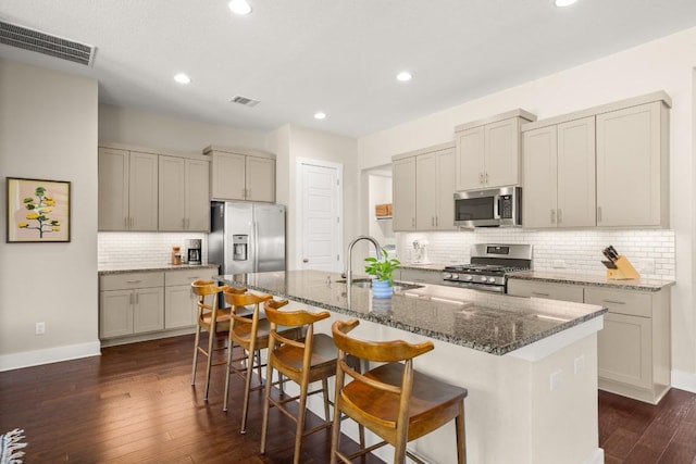 1609 Indian Apple Way, Leander, TX 78641 - kitchen with appliances with stainless steel finishes, a sink, decorative backsplash, dark wood-style floors, and a breakfast bar