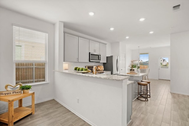637 Pickrell Loop, Liberty Hill, TX 78642 - kitchen featuring stainless steel appliances, light wood finished floors, a breakfast bar area, recessed lighting, and a peninsula