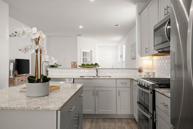 637 Pickrell Loop, Liberty Hill, TX 78642 - kitchen with a sink, appliances with stainless steel finishes, backsplash, light stone countertops, and a center island