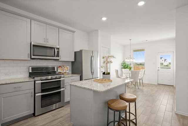 637 Pickrell Loop, Liberty Hill, TX 78642 - kitchen featuring stainless steel appliances, gray cabinets, light wood-type flooring, tasteful backsplash, and a chandelier