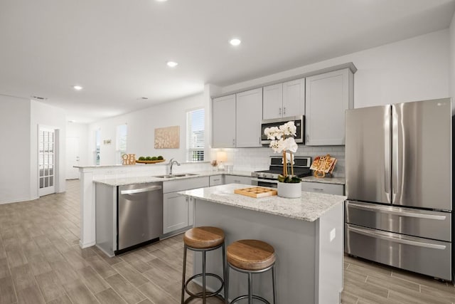637 Pickrell Loop, Liberty Hill, TX 78642 - kitchen featuring stainless steel appliances, a sink, a peninsula, backsplash, and light wood-style flooring