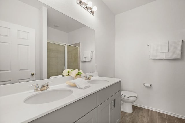 637 Pickrell Loop, Liberty Hill, TX 78642 - bathroom featuring toilet, double vanity, a stall shower, wood finished floors, and baseboards