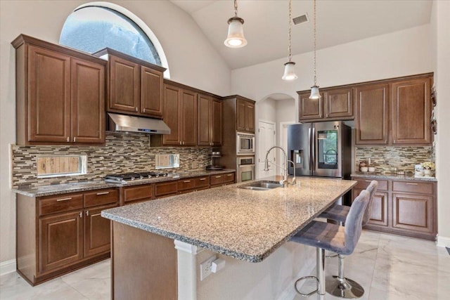 2997 Agave Loop, Round Rock, TX 78681 - kitchen with under cabinet range hood, light marble finish flooring, appliances with stainless steel finishes, a kitchen breakfast bar, and light stone countertops
