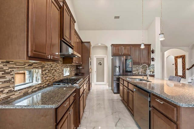 2997 Agave Loop, Round Rock, TX 78681 - kitchen featuring appliances with stainless steel finishes, under cabinet range hood, arched walkways, tasteful backsplash, and light marble finish floors