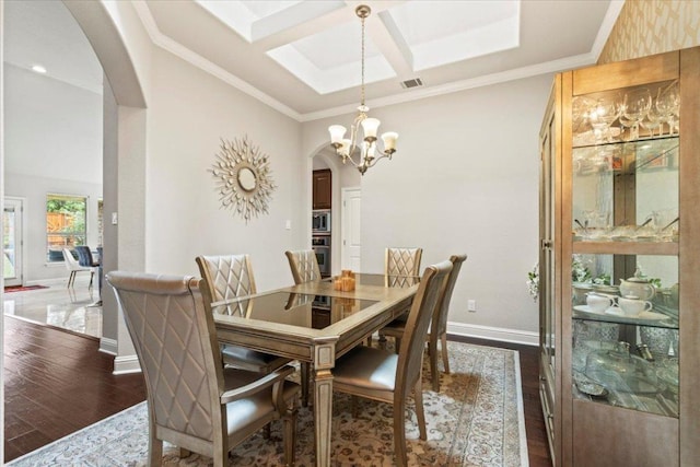 2997 Agave Loop, Round Rock, TX 78681 - dining area featuring arched walkways, dark wood-type flooring, a chandelier, coffered ceiling, and ornamental molding