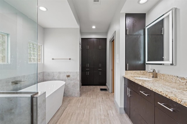 148 Oak Plaza Dr, Georgetown, TX 78628 - bathroom featuring a soaking tub, vanity, tile walls, recessed lighting, and walk in shower