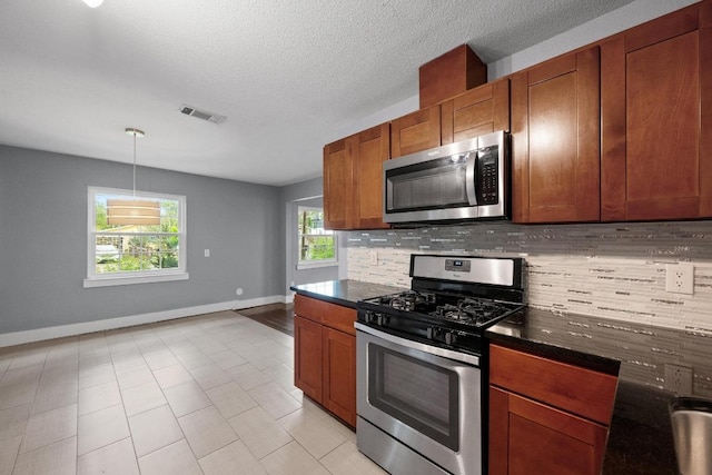 5601 Samuel Huston Ave, Austin, TX 78721 - kitchen with stainless steel appliances, tasteful backsplash, baseboards, brown cabinets, and light tile patterned floors