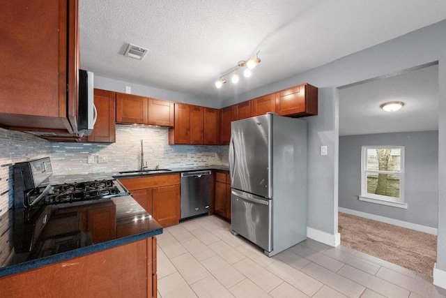 5601 Samuel Huston Ave, Austin, TX 78721 - kitchen featuring stainless steel appliances, a sink, decorative backsplash, brown cabinetry, and a textured ceiling