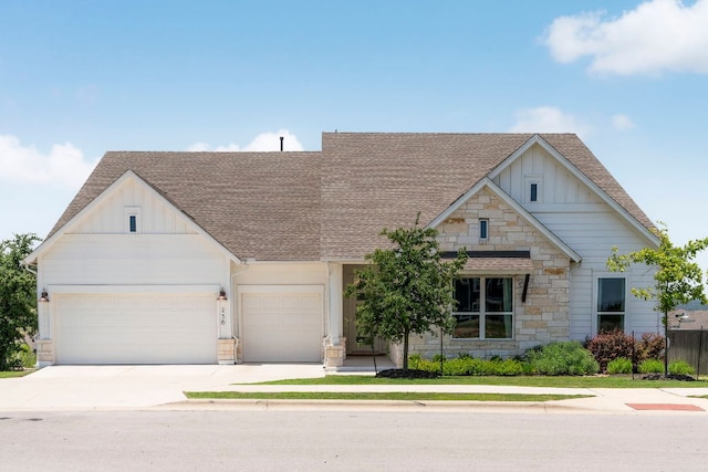256 Smoke Tree Cir, Dripping Springs, TX 78620 - view of front of property featuring board and batten siding, roof with shingles, stone siding, driveway, and a garage