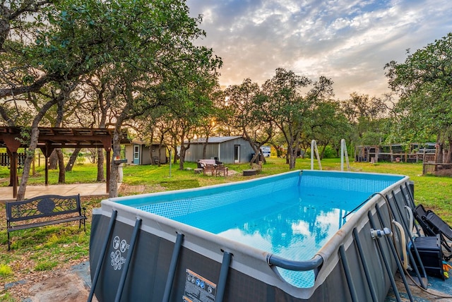 1181 Live Oak Trl, Liberty Hill, TX 78642 - pool at dusk with a yard, an outdoor pool, an outbuilding, and view of scattered trees