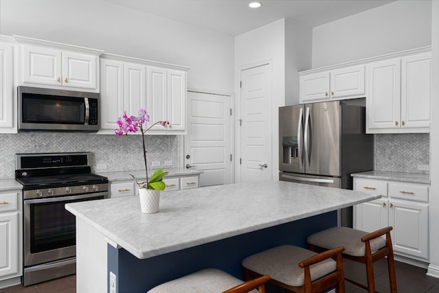 1518 Frontier Valley Dr, Austin, TX 78741 - kitchen with stainless steel appliances, a breakfast bar area, white cabinetry, a center island, and backsplash