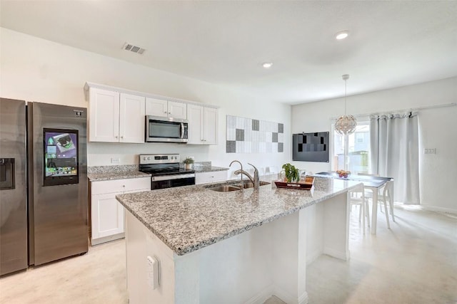 163 Wonderful Life Way, Jarrell, TX 76537 - kitchen with appliances with stainless steel finishes, a sink, white cabinets, light stone countertops, and a center island with sink
