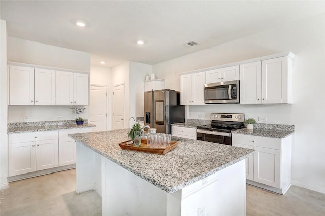 163 Wonderful Life Way, Jarrell, TX 76537 - kitchen featuring appliances with stainless steel finishes, white cabinetry, an island with sink, light stone countertops, and recessed lighting