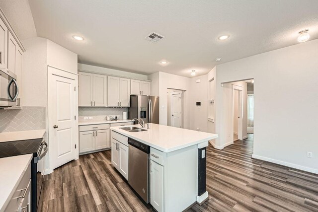 506 Hendelson Ln, Hutto, TX 78634 - kitchen featuring stainless steel appliances, dark wood-style flooring, light countertops, a kitchen island with sink, and recessed lighting