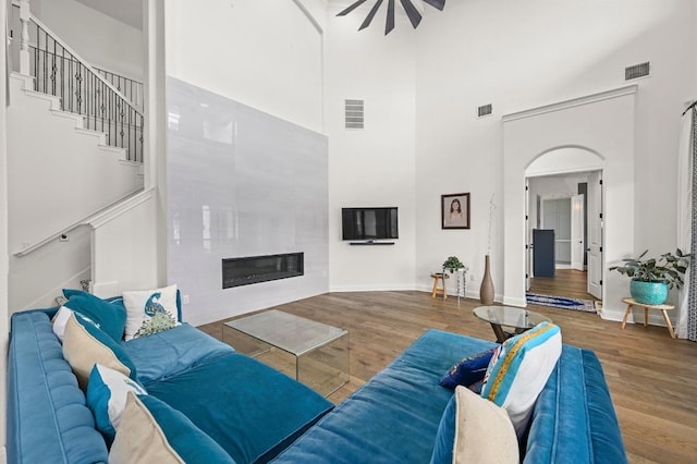 2625 Arion Cir, Austin, TX 78730 - living room with a high ceiling, a tile fireplace, wood finished floors, baseboards, and arched walkways