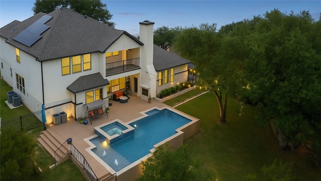 2625 Arion Cir, Austin, TX 78730 - back of property featuring a balcony, a chimney, roof mounted solar panels, a patio, and central AC unit