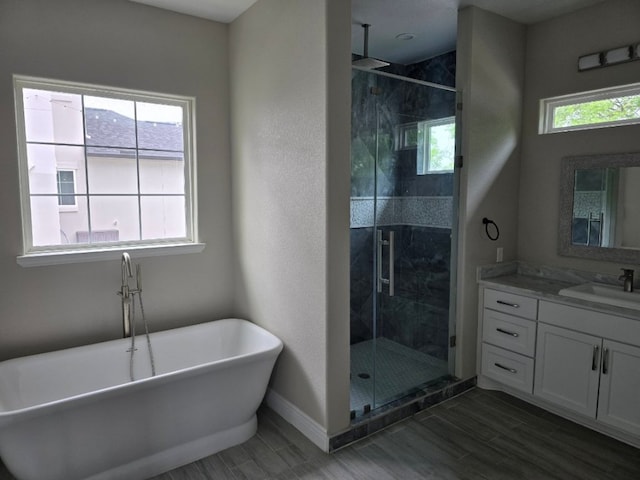 128 Gloria Blvd, Smithville, TX 78957 - bathroom featuring vanity, a stall shower, a soaking tub, and wood finished floors