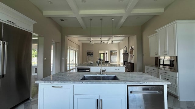 128 Gloria Blvd, Smithville, TX 78957 - kitchen featuring stainless steel appliances, coffered ceiling, a kitchen island with sink, light stone counters, and beamed ceiling